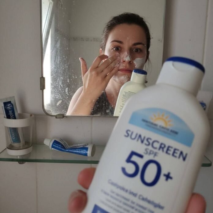 Hand applying sunscreen, mirror reflection.